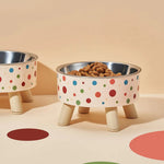 Polka dot pet bowls with wooden legs on a beige background