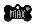 Black bone-shaped pet tag with 'max' and a paw print on a white background