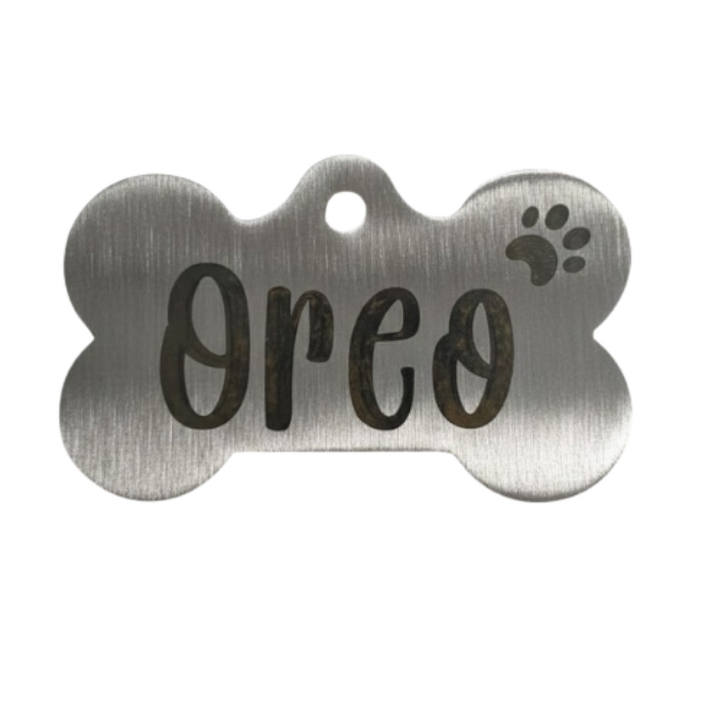 Metallic bone-shaped pet tag with 'Oreo' engraved on a white background
