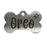 Metallic bone-shaped pet tag with 'Oreo' engraved on a white background