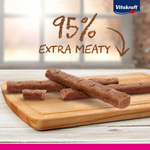 Dog treats on a wooden board with '95% Extra Meaty' text and Vitakraft logo.