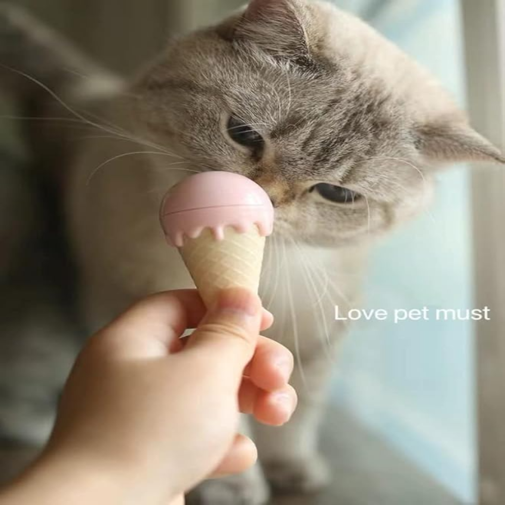 Cat sniffing a small pink ice cream cone held by a hand.