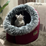 Cat inside a fluffy pet bed with 'Petmode' branding on a soft surface.