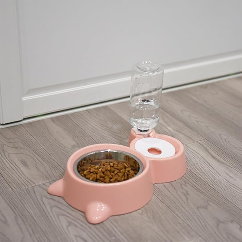 Pink pet feeder with a bowl of food and a water bottle on a wooden floor.