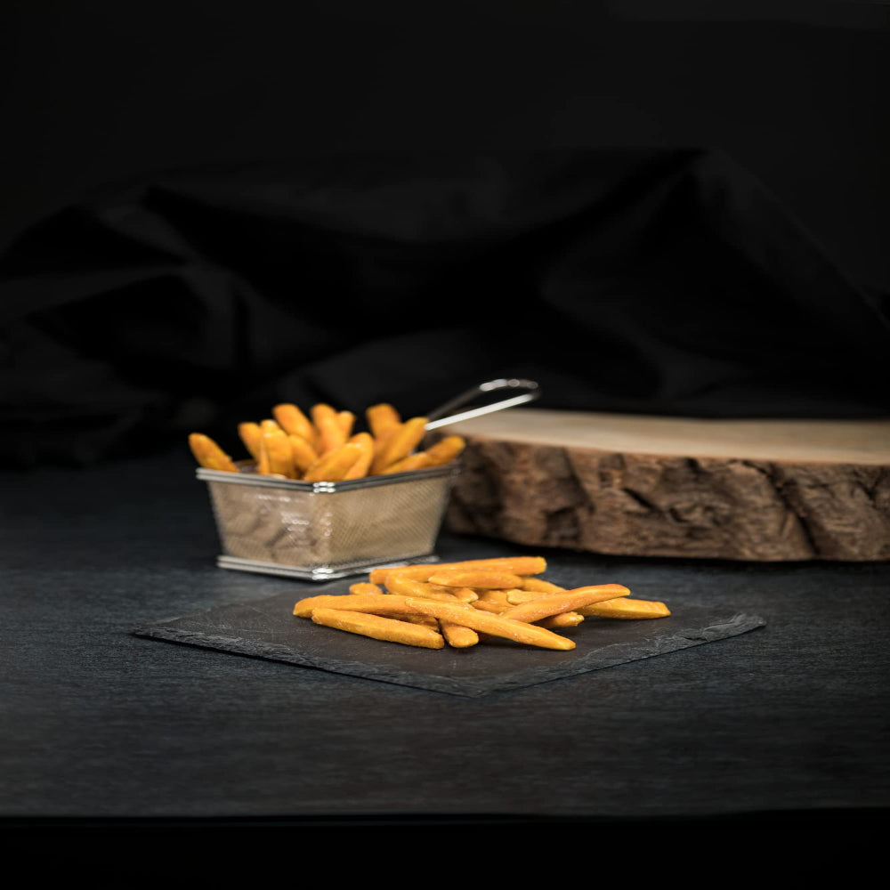 Fries in a small metal container on a dark surface with a black background