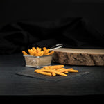 Fries in a small metal container on a dark surface with a black background