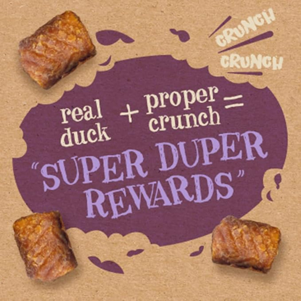 Dog treats with a purple speech bubble on a brown background, featuring text about 'real duck + proper crunch = Super Duper Rewards'.