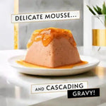 Delicate mousse with cascading gravy on a white plate with a marble background.