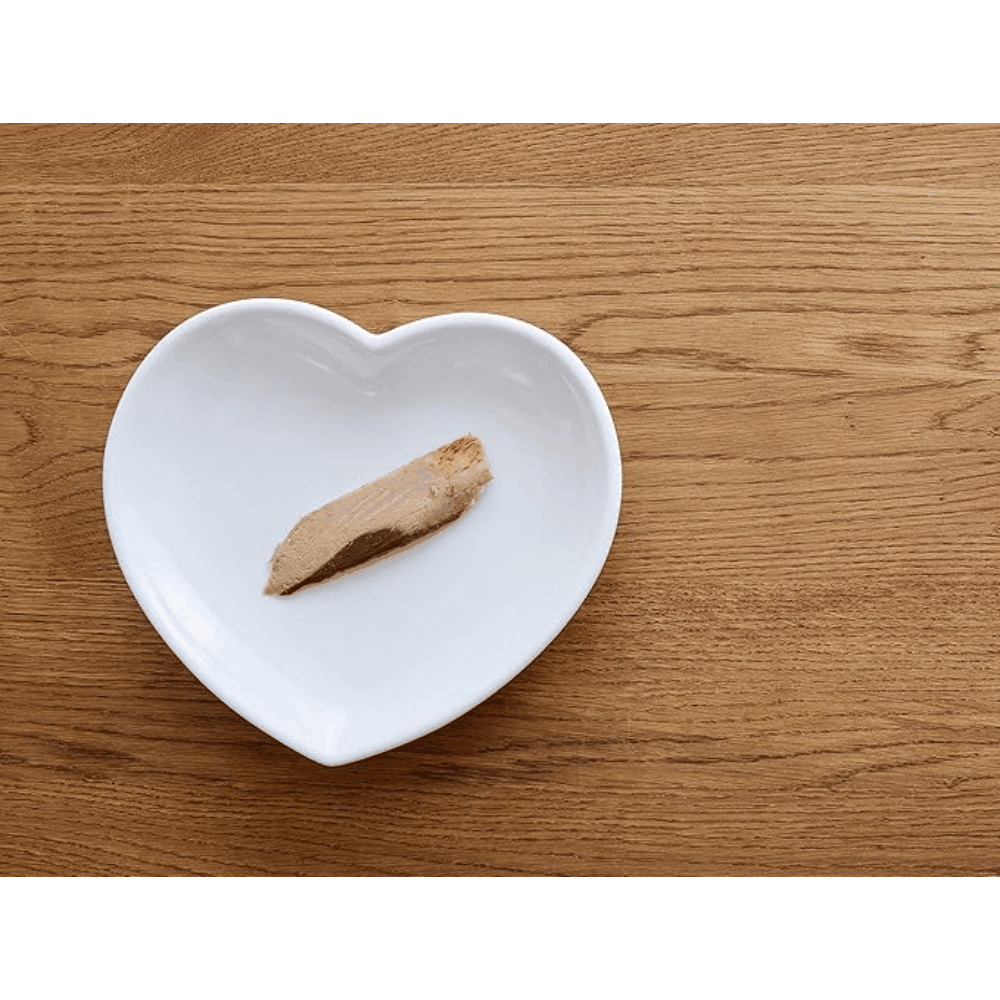 Heart-shaped white plate with a piece of foie gras on a wooden surface