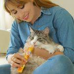 Woman holding a cat and a treat package, both wearing blue clothing.