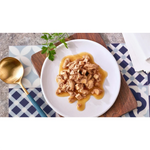 Plated dish of food with a gold spoon on a patterned tablecloth