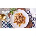 Plated dish of food with a gold spoon on a patterned tablecloth
