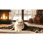 Cat sitting on a Christmas-themed blanket in a cozy living room with a fireplace and decorated tree.