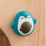 Teal shark-shaped object with a white mouth on a wooden surface