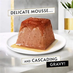 Delicate mousse dessert with cascading gravy on a white plate, set against a neutral background.
