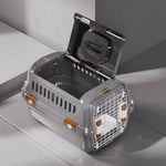Gray pet carrier with open lid on a light gray surface
