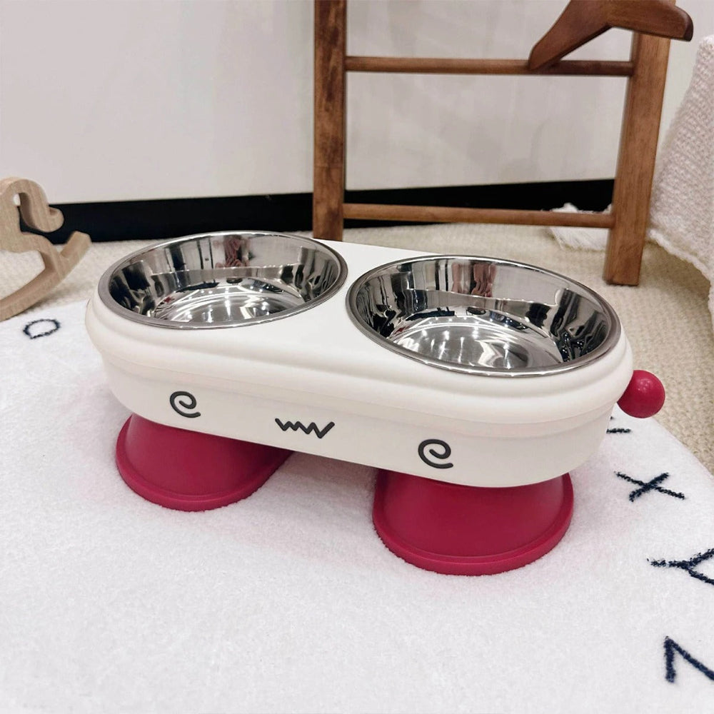 Pet food bowl with two stainless steel bowls on a pink base, placed on a white surface.