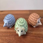 Three hedgehog-shaped stress balls on a wooden surface