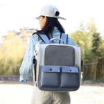 Person wearing a large gray backpack with a pet carrier on a blurred outdoor background