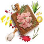 Raw chicken pieces on a wooden cutting board with herbs and spices on a white background