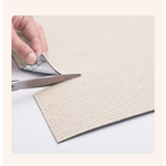 Person cutting a piece of textured beige paper with scissors on a white background