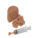 Block of brown cheese with crumbles and a syringe on a white background