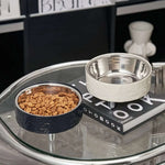Two bowls, one with kibble and the other empty, on a glass table.