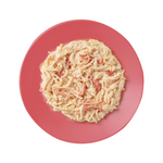 Pink plate with creamy pasta dish on a white background