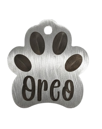 Metal paw-shaped pet tag with 'Oreo' engraved on a white background