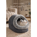 Gray pet bed with a cat inside, labeled 'Moda Grand Nest' by Petmoda, in a living room setting.