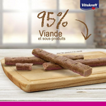 Dog treats on a wooden board with Vitakraft branding and text about meat content.