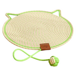 Round woven mat with a green border and a small green ball attached to a rope on a white background.