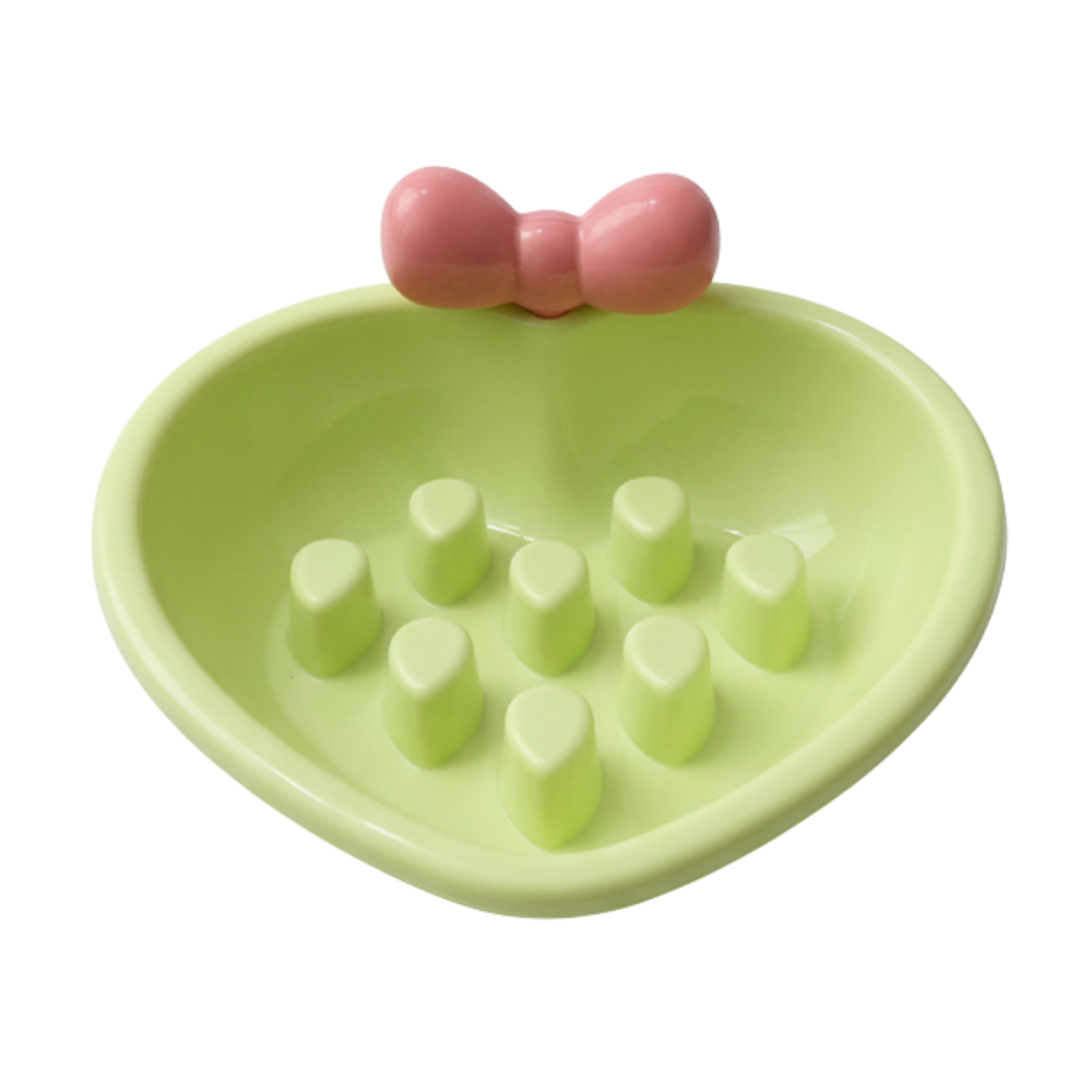 Green bowl with a pink bow and white cubes on a white background