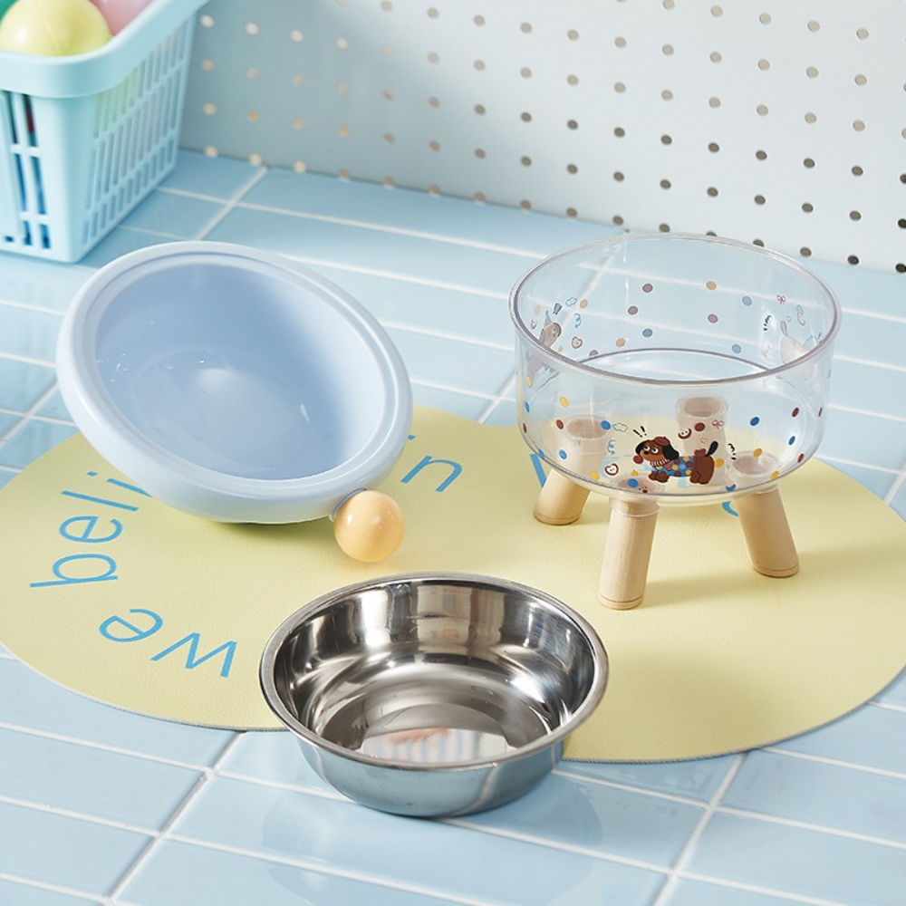 Three pet bowls on a mat with a polka dot wall in the background