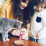 Woman and child with a cat and Twin Pack pet food at a table