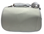 Light gray textured bag on a tiled floor with a wooden wall in the background
